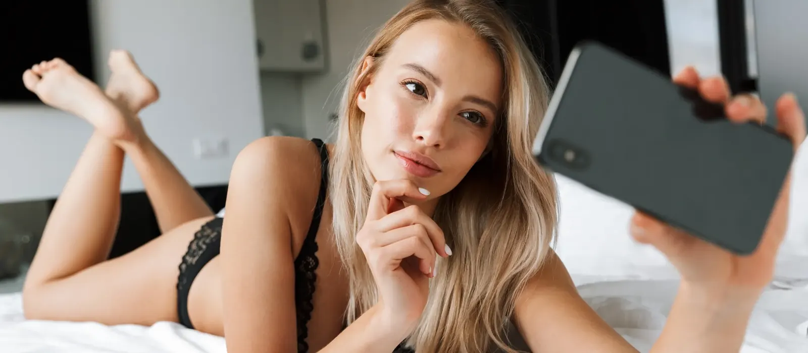 Hôtesse blonde allongée qui tend son téléphone, numéro de téléphone rose visio pour la Belgique
